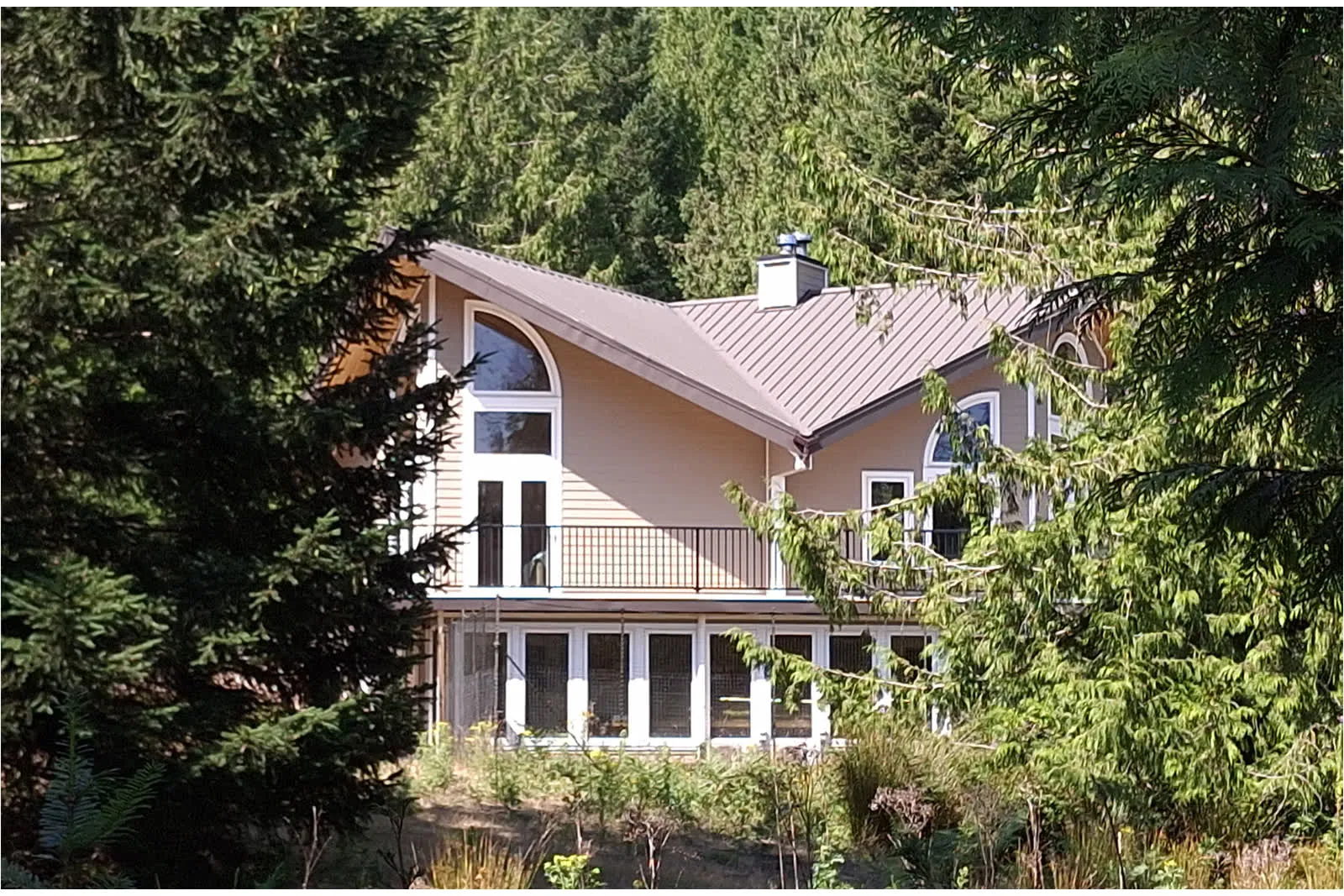 A Mayne Island home set among coastal forest along a wooded driveway.